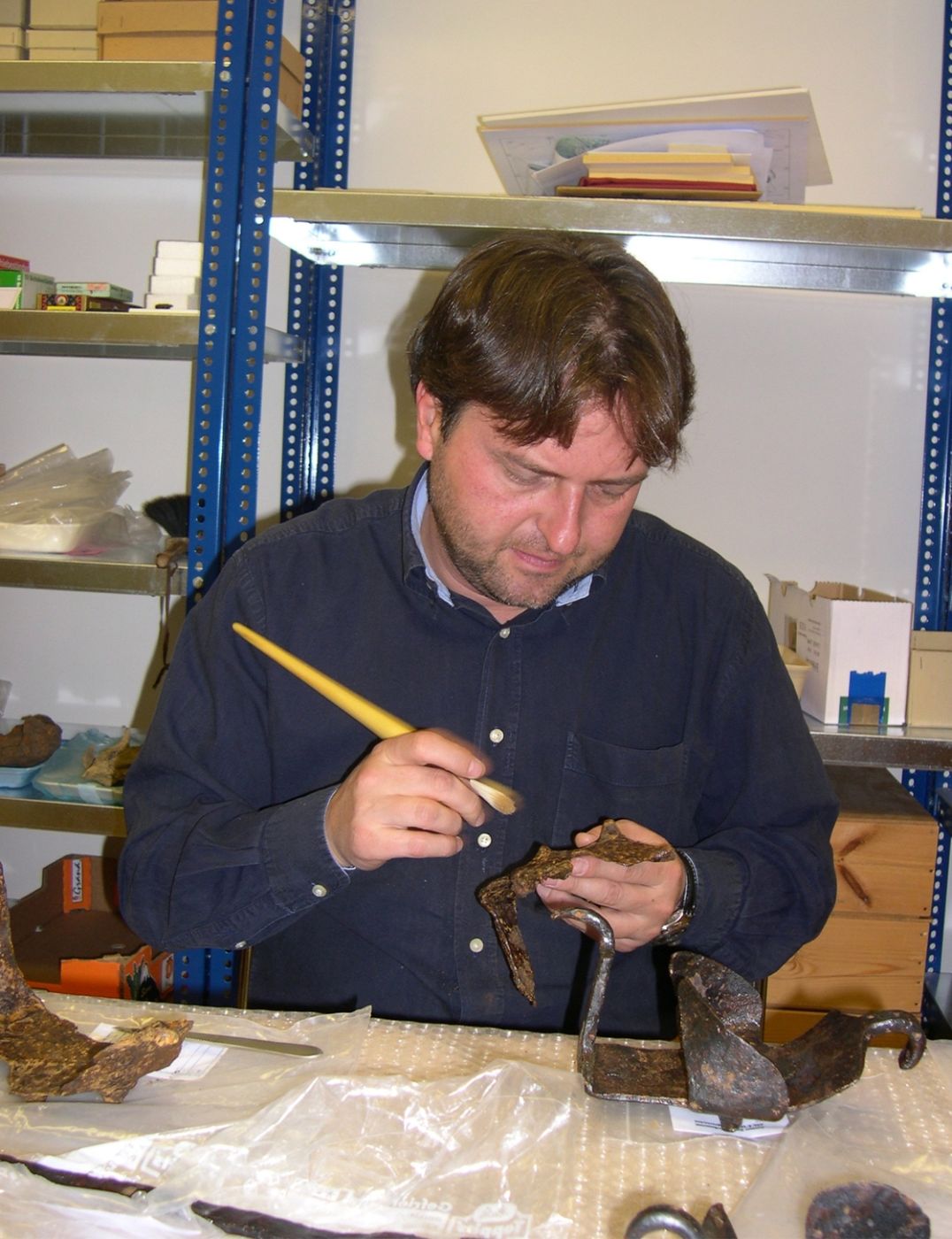 Ein Mann arbeitet in einem Labor mit einem Pinsel an der Restaurierung und Konservierung von antiken Sandalen
